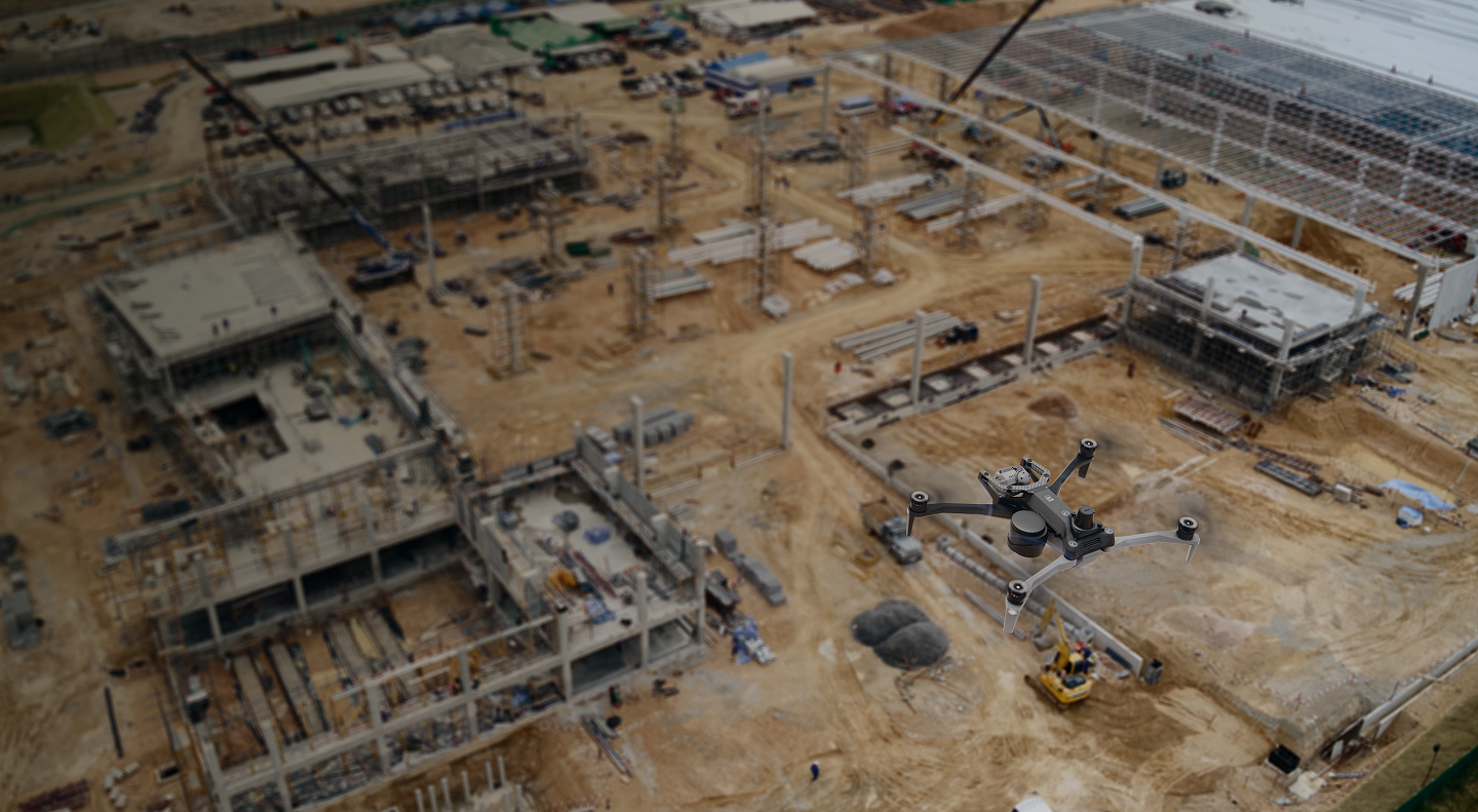 image overhead of Skydio X10 drone with parachute and RTK/PPK GPS attachments flying over a construction site