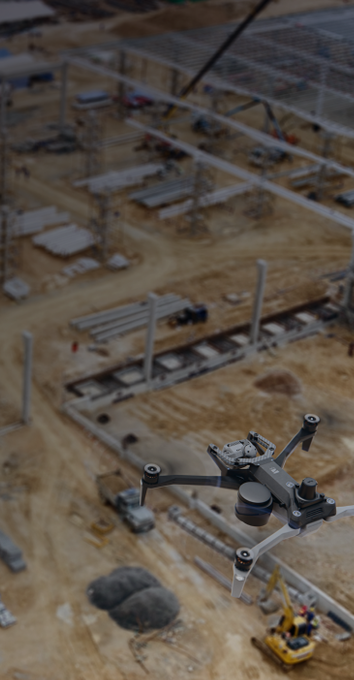 close image overhead of Skydio X10 drone with parachute and RTK/PPK GPS attachments flying over a construction site